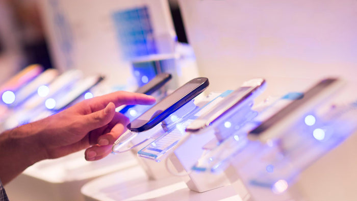 closeup photo of hand touching phone with more phones in the background