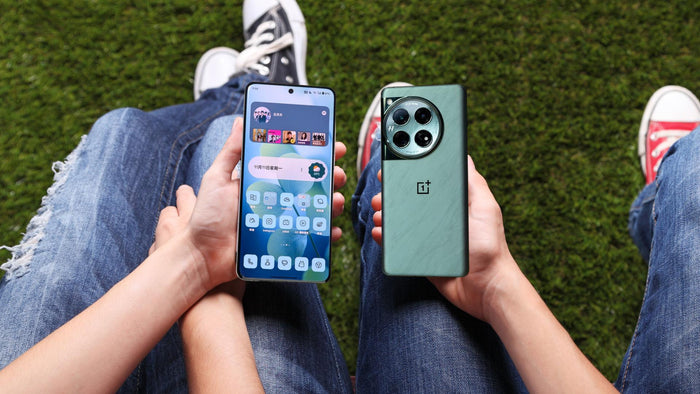 Two people comparing the OnePlus 13 and OnePlus 12